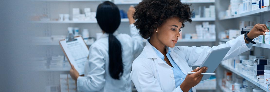 A woman looks through medication while comparing to a tabletin a hospital medication room